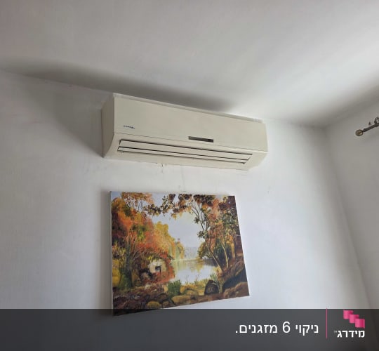 מזגן תלוי על קיר עם תמונה מתחתיו